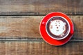 Hot cocoa and face cat milk foam in the red cup on wood background Royalty Free Stock Photo