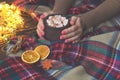 Hot cocoa with marshmallow in hand girl in knitted sweater, blanket and dry oranges with christmas lights. Christmas, winter, New Royalty Free Stock Photo