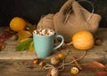 Hot cocoa with marshmallows in a blue ceramic mug with autumn leaves and pumpkins on a wooden table. The concept of hygge, cozy Royalty Free Stock Photo