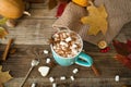 Hot cocoa with marshmallows in a blue ceramic mug with autumn leaves and pumpkins on a wooden table. The concept of hygge, cozy Royalty Free Stock Photo