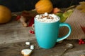 Hot cocoa with marshmallows in a blue ceramic mug with autumn leaves and pumpkins on a wooden table. The concept of hygge, cozy Royalty Free Stock Photo