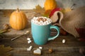 Hot cocoa with marshmallows in a blue ceramic mug with autumn leaves and pumpkins on a wooden table. The concept of hygge, cozy Royalty Free Stock Photo