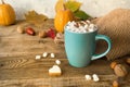 Hot cocoa with marshmallows in a blue ceramic mug with autumn leaves and pumpkins on a wooden table. The concept of hygge, cozy Royalty Free Stock Photo