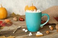 Hot cocoa with marshmallows in a blue ceramic mug with autumn leaves and pumpkins on a wooden table. The concept of hygge, cozy Royalty Free Stock Photo