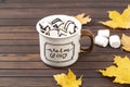 Hot cocoa with marshmallows in a ceramic mug on a wooden table. The concept of a cozy holiday.