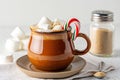 hot cocoa mug with marshmallows and candy cane resting beside cozy kitchen glow Royalty Free Stock Photo