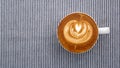 Hot coffee cappuccino latte art flower shape top view on navy stripe fabric background Royalty Free Stock Photo