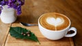 Hot coffee cappuccino latte art heart shape in ceramic cup on wood plate