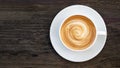 Hot coffee cappuccino latte spiral foam top view on dark wood background