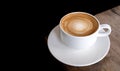 Hot coffee cappuccino spiral foam on wooden table on black background