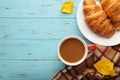 Hot coffee with croissant and autumn leaves on blue - seasonal relax concept