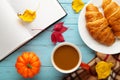 Hot coffee with croissant and autumn leaves on blue - seasonal relax concept