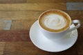 Hot coffee cup cappuccino or latte with stirred spiral milk foam on multicolor plank wood table background in the morning Royalty Free Stock Photo