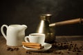 hot coffee cup with cinnamon sticks with a creamer and old pot/hot coffee cup with cinnamon sticks with a creamer and old pot on a Royalty Free Stock Photo