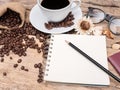 Hot coffee cup with coffee bean and notebook with pencil on wooden table. coffee background menu for cafe or coffee shop Royalty Free Stock Photo