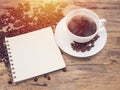 Hot coffee cup with coffee bean and notebook on wooden table. Royalty Free Stock Photo