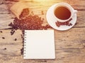 Hot coffee cup with coffee bean and notebook on wooden table Royalty Free Stock Photo