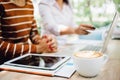 Hot coffee cup of latte art, coffee on wooden table in the morning, with people Discussing, work together on a laptop background. Royalty Free Stock Photo