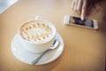 Hot of coffee drink on wooden table bar with mobile phone Royalty Free Stock Photo