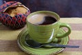 Hot coffee in a green cup with blurred sugar pot of brown sugar in backdrop served on stripe tablecloth Royalty Free Stock Photo