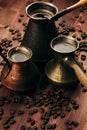 Hot coffee in group shabby antique turkish pots cezve with crem, beans with blur on brown old wooden board background, vertical sh Royalty Free Stock Photo