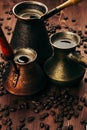 Hot coffee in group shabby antique turkish pots cezve with crema, beans with blur on brown old wooden board background, vertical s Royalty Free Stock Photo