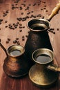 Hot coffee in group shabby antique turkish pots cezve with crema, beans with blur on brown old wooden board background, vertical s Royalty Free Stock Photo