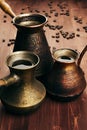 Hot coffee in group shabby antique turkish pots cezve with crema, beans with blur on brown old wooden board background, vertical s Royalty Free Stock Photo