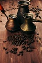 Hot coffee in group shabby antique turkish pots cezve with crema, beans with blur on brown old wooden board background, vertical s Royalty Free Stock Photo