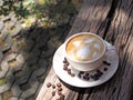 Hot coffee with heart shape, latte art in a white cup with coffee beans, on a wooden table in the garden. Royalty Free Stock Photo