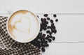 Hot coffee latte art and beans,brown cloth Tartan on white cup with on clean wood background. Top view copy space for your text Royalty Free Stock Photo