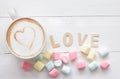 Hot coffee latte art and Colorful marshmallows on white cup with on clean wood background. Top view copy space for your text Royalty Free Stock Photo