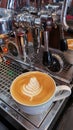 Hot coffee latte served in a white cup and saucer on coffee machine