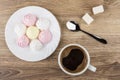 Hot coffee, meringues in plate, sugar and spoon on table