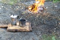 Hot coffee in a metal cup with a geyser coffee maker on a wooden board near the fire. Royalty Free Stock Photo