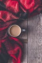 Hot coffee mug wrapped in a cozy red scarf for winter days on a wooden table Royalty Free Stock Photo