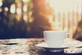 Hot coffee on old wood table with blur background of sunlight shining through the trees