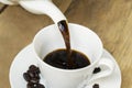 Hot coffee pouring into cup on wooden table Royalty Free Stock Photo