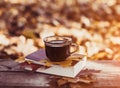 Hot coffee and red book with autumn leaves on wood background - seasonal relax concept Royalty Free Stock Photo