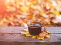 Hot coffee and red book with autumn leaves on wood background - seasonal relax concept Royalty Free Stock Photo