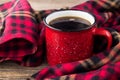 hot coffee in red cup and cozy plaid on wooden background