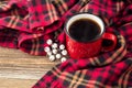 hot coffee in red cup and cozy plaid on wooden background