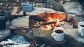 Hot coffee or tea in mugs near campfire. Hiking tourism concept