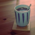 Hot coffee with a teaspoon in Japanese cup on bamboo coaster. Royalty Free Stock Photo