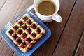 Hot coffee and Waffles with chocolate sauce on wooden table background.