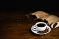 Hot coffee in a white coffee cup and many coffee beans placed around on a wooden table in a warm, light atmosphere, on dark Royalty Free Stock Photo