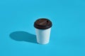 Hot coffee in white paper cup with black lid on blue background Royalty Free Stock Photo