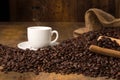 Hot coffeecup with spilled beans on table Royalty Free Stock Photo