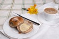 Hot cross bun cut and buttered on a white plate cup of tea napkin Royalty Free Stock Photo