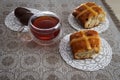 Hot cross buns, cup of tea and chocolate eggs on easter table Royalty Free Stock Photo